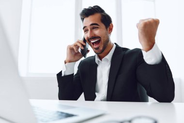 Ofis işadamı masasında oturuyor ve dizüstü bilgisayarda çalışıyor ve telefonla konuşuyor, modern takım elbise, finans ve başlangıç konsepti ve veri analizi, parlak bir ofiste çalışma tarzı. Yüksek kalite fotoğraf