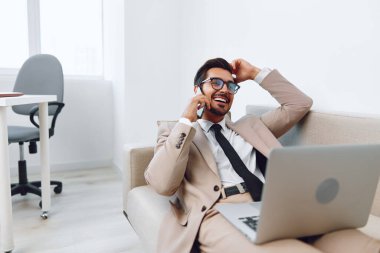 Bilgisayar adamı iş adamı başarı yöneticisi telefon teknolojisi video kostüm gülümseme telefon akıllı telefon insanlar bağlantı beyaz laptop konuşma iş adamı bej mobil iş koltuğu