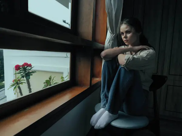 Woman fall depression sitting by the window and looking at nature, rainy weather and discouragement, home life style, loneliness. High quality photo