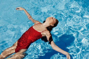 Kırmızı mayo içinde yüzen, uzun saçlı, güneş kremli cilt koruması olan, tatilde rahatlama konsepti olan mutlu bir kadın. Yüksek kalite fotoğraf