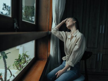 Kadın depresyona girer ve pencerenin kenarında oturur ve doğaya bakar, yağmurlu hava ve hayal kırıklığı, ev hayatı tarzı, yalnızlık. Yüksek kalite fotoğraf