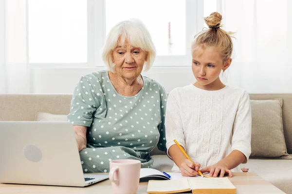 Grandmother photography family togetherness call bonding education selfie indoors child sofa smiling two happiness space adult t-shirt senior people granddaughter video hugging copy white laptop