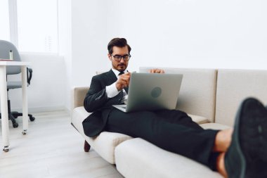 Adam rahatlamış insan ağları kuruyor beyaz koltukta oturan başarılı iletişim kuran adam kanepe laptopu kullanıyor yetişkin erkek yakışıklı video evini arıyor çevrimiçi gülümsüyor.