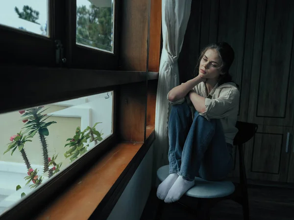 Woman fall depression sitting by the window and looking at nature, rainy weather and discouragement, home life style, loneliness. High quality photo
