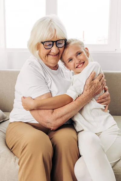 Woman family home lifestyle girl old couch hugging bonding happy elderly grandmother love sofa child mother granddaughter hug