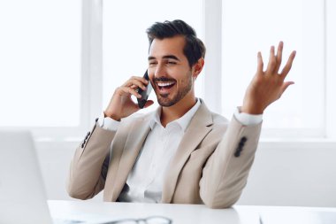 Bilgisayarlı adam gülümsemesi Kafkasyalı çağrı bej telefon kablosuz iş yeri yöneticisi cep telefonu mutlu bağlantı telefonu iş adamı görünümlü akıllı dizüstü bilgisayar modern sohbet