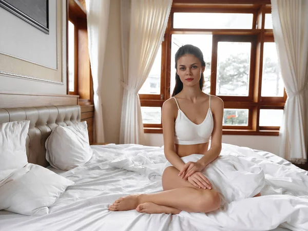 布吕内特年轻女子躺在床上 裹着白色毯子 待在家里 性感的年轻女人醒来后穿着内衣 性感的身体在现代公寓里 高质量的照片 — 图库照片