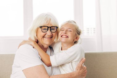 Yaşlı aile çocuğuna sarılan bir kadın. Torunu, büyükannesi, yaşam tarzını seven mutlu bir anne kanepesi.