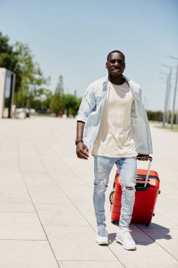 Delikanlı valiz modacısı yakışıklı erkek yakışıklı arka plan sokak yaşam tarzı Afrikalı çantalı modern açık hava modeli mutlu insan seyahati
