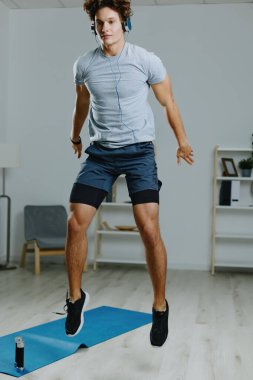 Erkek zeminindeki beden eğitimi egzersizini evde izleyin. Çevrimiçi genç sağlıklı insanlar spor kıyafetleri yaşam tarzı gri sağlık aktiviteleri kulaklıklar kaslı kulaklıklar.