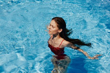 Havuzda yüzen kırmızı mayo, güneş ışığında uzun saçlar, güneş kremli cilt koruması, tatilde dinlenme konsepti. Yüksek kalite fotoğraf