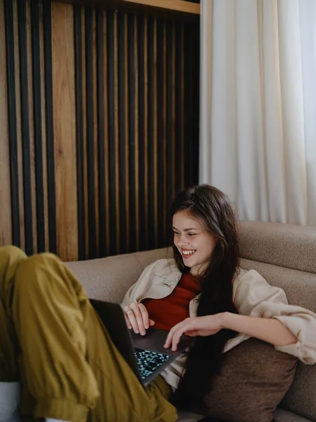 Eine Frau Liegt Mit Einem Laptop Auf Dem Sofa Und — Stockfoto