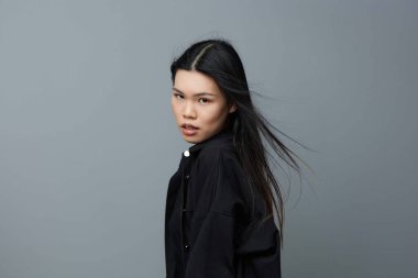 Kadın mutlu bir gülümsemeyle, güzel bir saçla, arka planla, gri sağlıklı bir fotoğrafla, doğal bir vesikalık fotoğrafla, kahverengi bir kızla, çekici bir Asyalı güzel bir portreyle karşı karşıya.