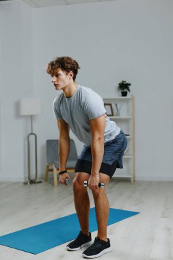 Spor salonunun spor salonundaki erkek dambılları evde gri yaşam eğitimi veriyor.