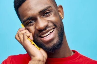 arka plan adamı mesajı Afrikalı yaşam tarzı çevrimiçi genç siyah teknoloji portresi mavi renkli moda cep telefonu gülümsemesi mutlu cep telefonu modeli