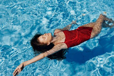 Kadın spor yaşam tarzı, genç mavi yaz bikinisi, su altında ıslak kadın havuz görevlisi, vücut suyunda yüzer.