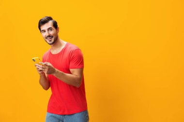 Gözlüklü adam Stüdyo 'nun dişlek telefonunun kopyası mutlu gülümseyen cep telefonu sarı iletişim siber uzay teknolojisi mesaj mesajı sürpriz gülümsemesi izole edilmiş yaşam tarzı akıllı telefon portresi işi