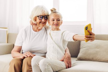 Torun beyaz, büyükanneyi arıyor, video kopyalarını sarılıyor, uzay eğitiminde gülümsüyor. Çocuklar, aile üyeleri, iki kanepe, selfie tişörtü.
