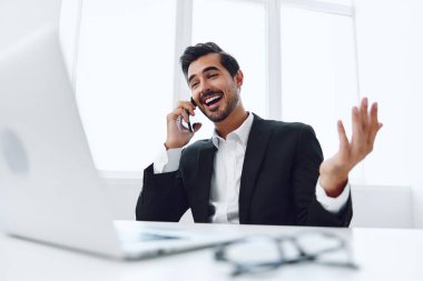 Ofis işadamı masasında oturuyor ve dizüstü bilgisayarda çalışıyor ve telefonla konuşuyor, modern takım elbise, finans ve başlangıç konsepti ve veri analizi, parlak bir ofiste çalışma tarzı. Yüksek kalite fotoğraf