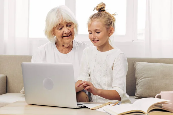 Bonding grandmother smiling video laptop space education granddaughter call togetherness indoors copy child white photography sofa selfie family hugging t-shirt