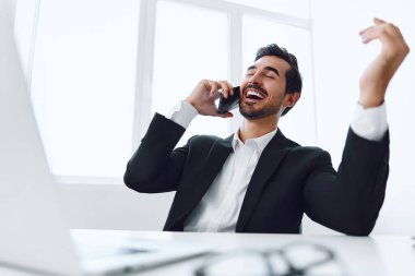 Ofis işadamı masasında oturuyor ve dizüstü bilgisayarda çalışıyor ve telefonla konuşuyor, modern takım elbise, finans ve başlangıç konsepti ve veri analizi, parlak bir ofiste çalışma tarzı. Yüksek kalite fotoğraf