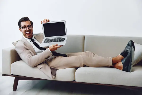 Business man hunk networking smiling entrepreneur casual call video using couch laptop communication looking indoors online sofa house home successful guy freelance