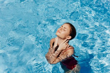 Kırmızı mayo içinde yüzen, uzun saçlı, güneş kremli cilt koruması olan, tatilde rahatlama konsepti olan mutlu bir kadın. Yüksek kalite fotoğraf