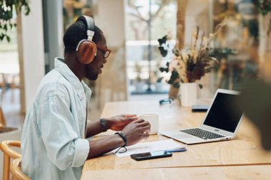 Erkek müzik kulaklığı ofis teknolojisi iletişimi çevrimiçi kablosuz genç erkek kulaklıklar kulaklıklar bilgisayar işadamı iş adamı iş adamı laptopu dinliyor