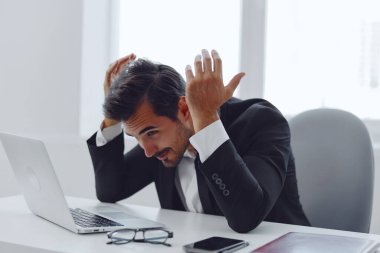 Sıradan, yakışıklı, sorunlu bir yönetici gözlüklü, yetişkin, laptop teknolojili, stresli, iş yeri görünümlü, mutsuz, oturma masasında oturan bir adam.