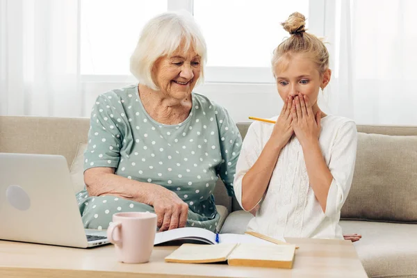 Adult child indoors family laptop space white grandmother education selfie happiness call video hugging t-shirt people copy senior photography togetherness sofa granddaughter smiling bonding two