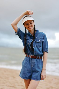 Şık Yaz Portresi: Beyaz Sahilde Oturan Çekici Kadın, Mavi Okyanus Arkaplanı ile Mutlu ve Güzel Görünüyor