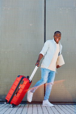 Model adam yürüyen arka planda yetişkin görünümlü çanta yakışıklı yakışıklı seyahat çekici havalı turist ifadesi bavul genç, pozitif, modern yaşam tarzı yolcusu.