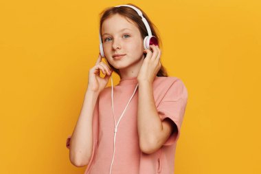 Modern teknolojinin tadını çıkaran küçük bir kız: Müzik ve kulaklıkla öğrenmenin eğlenceli anları ve bir kitap