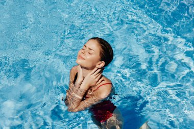 Kırmızı mayo içinde yüzen, uzun saçlı, güneş kremli cilt koruması olan, tatilde rahatlama konsepti olan mutlu bir kadın. Yüksek kalite fotoğraf