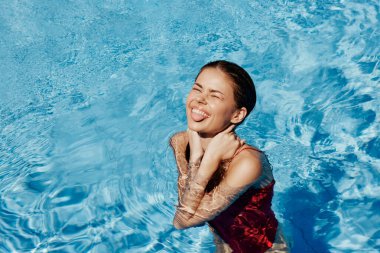 Kırmızı mayo içinde yüzen, uzun saçlı, güneş kremli cilt koruması olan, tatilde rahatlama konsepti olan mutlu bir kadın. Yüksek kalite fotoğraf