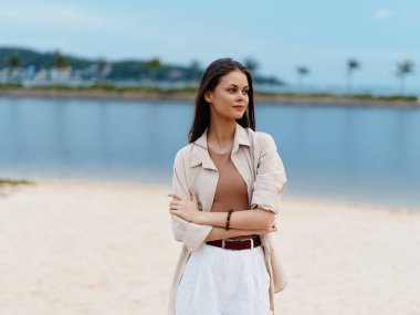 Güzel genç bayan, kendinden emin ve mutlu, Yazın açık havada, Denizin kenarında duruyor
