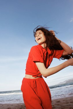 Neşeli Okyanus Esintisi: Güneşli bir sahilde özgürlük ve neşeyle dans eden gülümseyen bir kadın