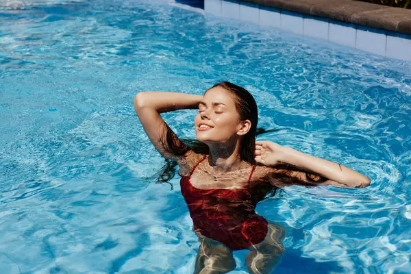 Kırmızı mayo içinde yüzen mutlu bir kadın, güneş ışığında uzun saçlar, güneş kremi ile cilt koruması, tropikal iklimde tatilde dinlenme kavramı. Yüksek kalite fotoğraf