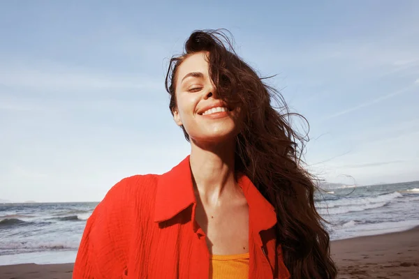 Smiling Woman Enjoying Freedom and Joy at the Beach under Sunny Blue Sky: Portrait of Happy Young Lady in Red Clothes