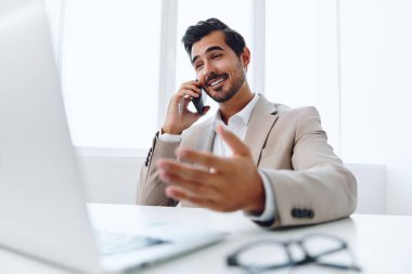Ofis işadamı masasında oturuyor ve dizüstü bilgisayarda çalışıyor ve telefonla konuşuyor, modern takım elbise, finans ve başlangıç konsepti ve veri analizi, parlak bir ofiste çalışma tarzı. Yüksek kalite fotoğraf