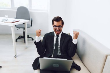 Rahatlamış, gülümseyen bir daire kullanan bir adam. İnternette başarılı bir dizüstü bilgisayar. Kanepe bağlantıları.