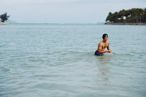トロピカルオーシャンで泳ぐ幸せなアジア人男性 ビーチでの休暇を楽しむ — ストック写真