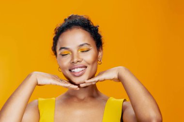 Kadın stüdyo modeli moda tarzıyla yüzleşiyor. Makyaj sarı portre güzel afrikalı gülümseme kozmetik renkli güzellik kozmetolojisi siyah yaratıcı ten