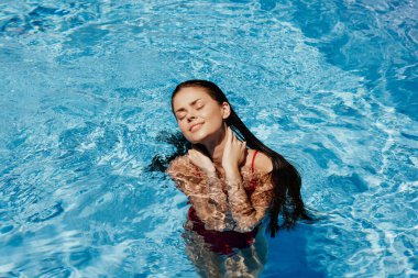 Havuzda yüzen kırmızı mayo, güneş ışığında uzun saçlar, güneş kremli cilt koruması, tatilde dinlenme konsepti. Yüksek kalite fotoğraf