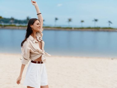 Doğada Güzellik: Çekici Genç Kadın Güneşli bir yaz plajında duruyor, Deniz Tarafından Tatilin ve Rahatlamanın tadını çıkarıyor