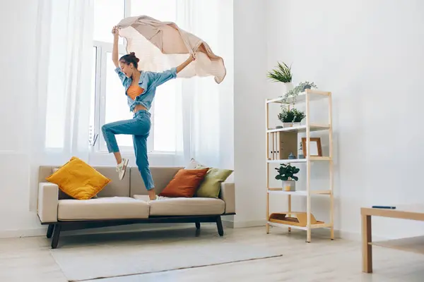 Jumping Joy in Home: Playful Woman Dancing with Excitement in Beautiful Apartment