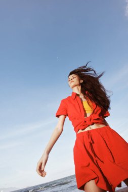 Yaz Saadeti: Güneşli bir plajda Kırmızı Giysilerle Dans Eden Gülümseyen Kadın