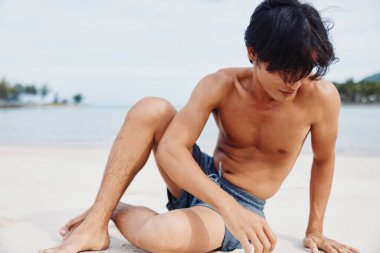 Kas yığını Asyalı atlet Sandy sahilinde koşuyor, Fitness yaşam tarzını kucaklıyor.