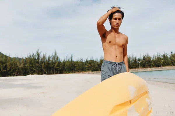 トロピカルビーチでハッピーなアジア人男性カヤック 太陽に照らされたパラダイスでの爽快なアドベンチャー — ストック写真