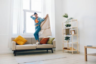 Neşeli Ev Atlayıcısı: Evde Rahatlatıcı Bir Apartmanda Dans Eden ve Mutlulukla Şarkı Söyleyen Oyuncu Bir Kadın